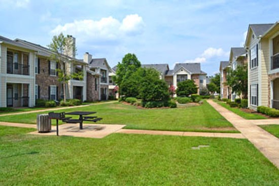 Riverwalk open green courtyard with tables and benches, sidewalk, apartment building surrounding