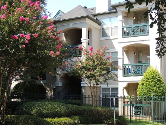 La Crosse Apartments up close side view of stunning three story white apartment building with green fence/railing