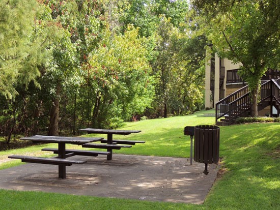 Riverbend Apartments picnic area two tables with benches, grill and covered by trees