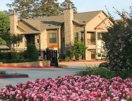 SpringRidge exterior of apartment buildings from outside of gates with stunning pink flowers and greenery