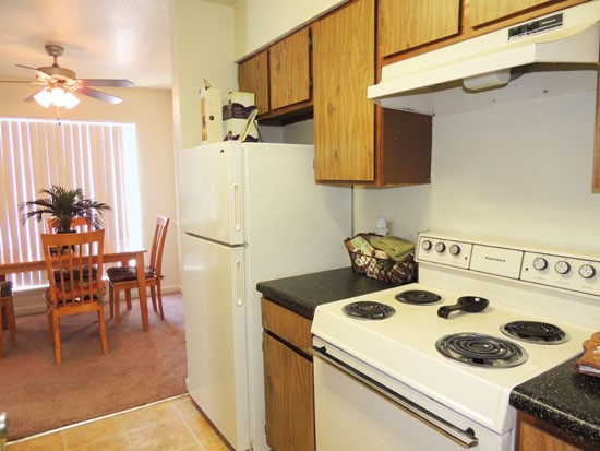 Tree Tops Apartments open model kitchen with wood cabinets looking into dining room area