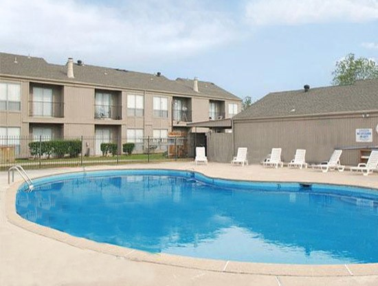 Tree Tops Apartments bean shaped pool with white pool side lounge chairs