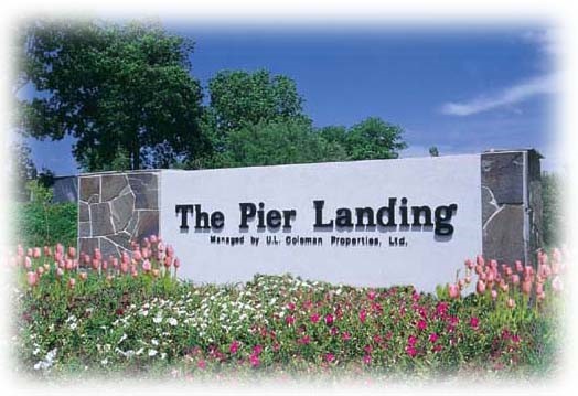 Pier Landing big long beautiful stone and white front sign with flowers in front